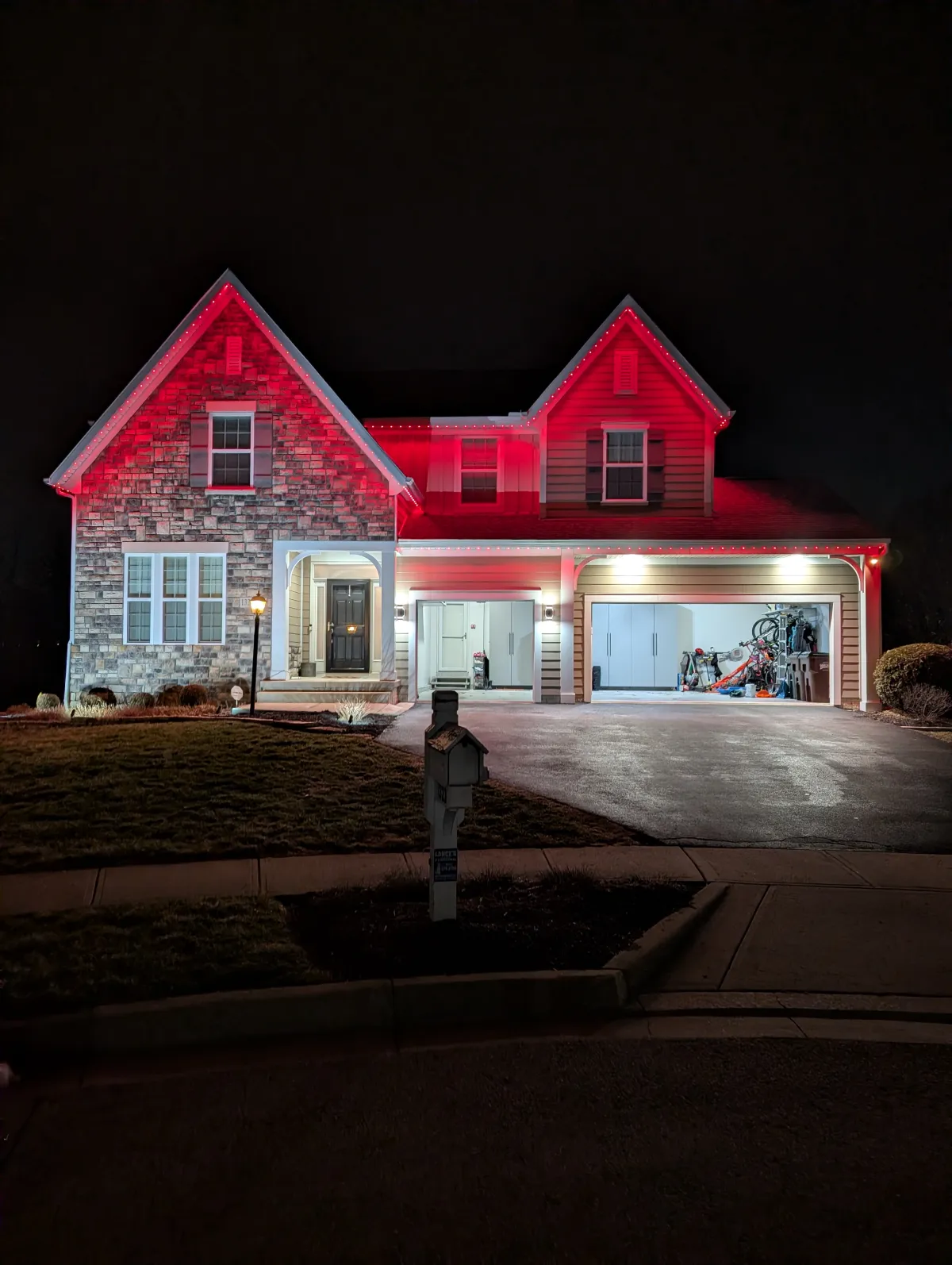 Red permanent lights on stone and siding two story home at night