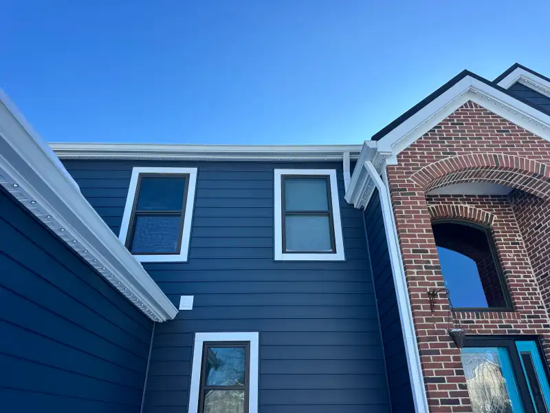 Permanent Christmas lights aluminum channel installed on a dark navy two story home in daytime, the channel disappears into the trim line